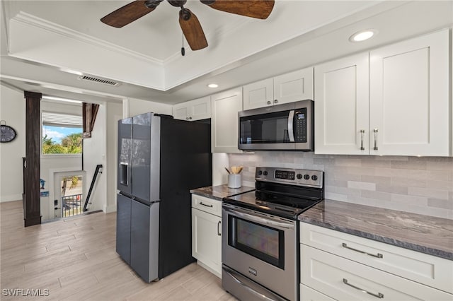 kitchen featuring white cabinets, appliances with stainless steel finishes, decorative backsplash, and ornamental molding