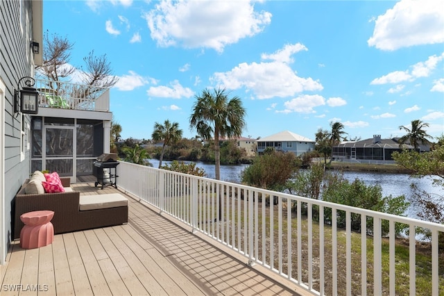 wooden deck featuring grilling area, a sunroom, and a water view