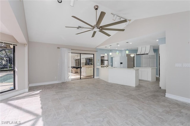 unfurnished living room with ceiling fan, rail lighting, and lofted ceiling