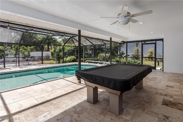 view of swimming pool featuring glass enclosure, ceiling fan, and a patio