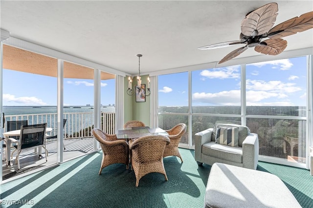 sunroom with ceiling fan and a water view