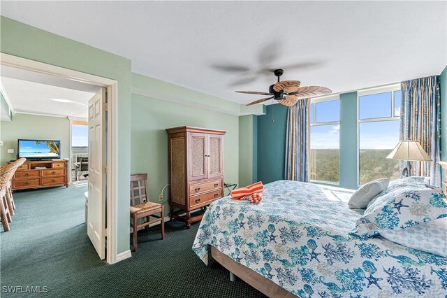 bedroom with dark colored carpet, a ceiling fan, and a wall of windows