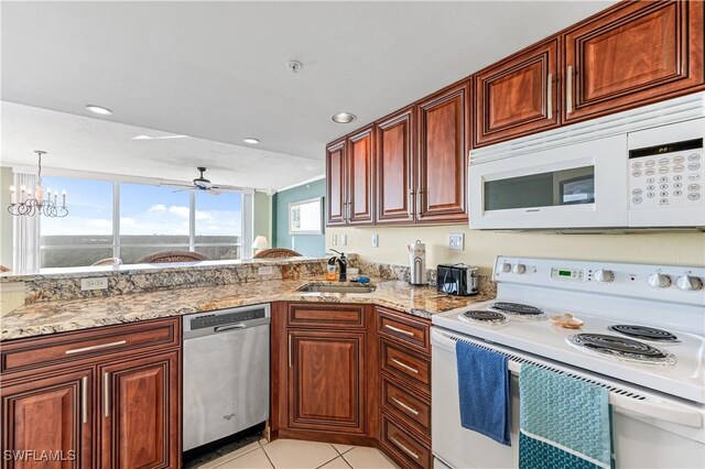 kitchen with light stone counters, hanging light fixtures, light tile patterned flooring, a sink, and white appliances