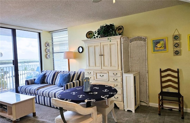 living room featuring floor to ceiling windows, ceiling fan, dark tile patterned flooring, and a textured ceiling