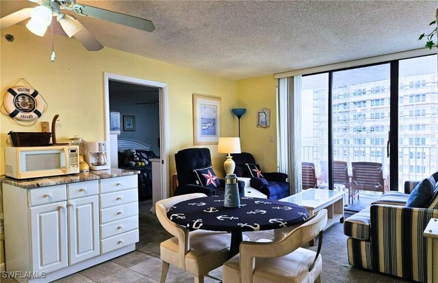 dining room with ceiling fan, floor to ceiling windows, a textured ceiling, and light tile patterned floors