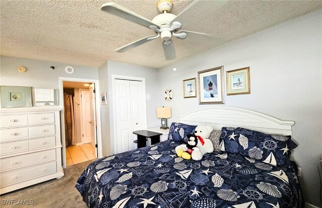 carpeted bedroom with ceiling fan, a closet, and a textured ceiling