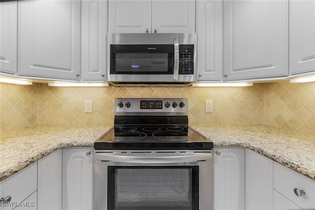 kitchen with appliances with stainless steel finishes, white cabinets, and backsplash