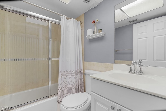 full bathroom featuring toilet, shower / tub combo with curtain, vanity, and tile walls