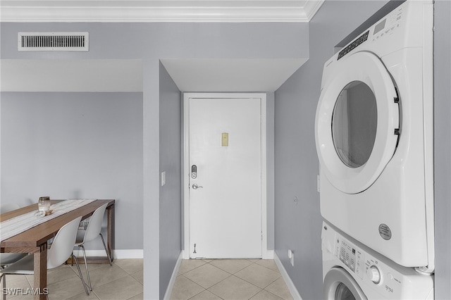 clothes washing area featuring crown molding, light tile patterned floors, and stacked washer and clothes dryer