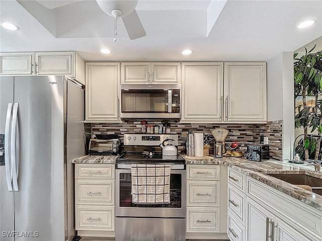 kitchen featuring tasteful backsplash, appliances with stainless steel finishes, light stone counters, and ceiling fan