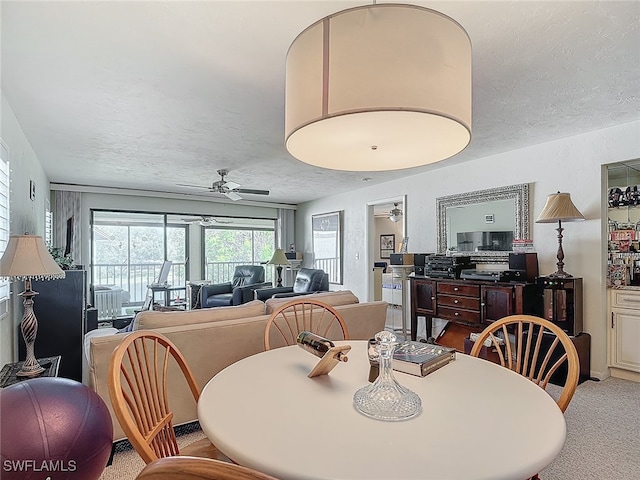 carpeted dining space with a textured ceiling and ceiling fan