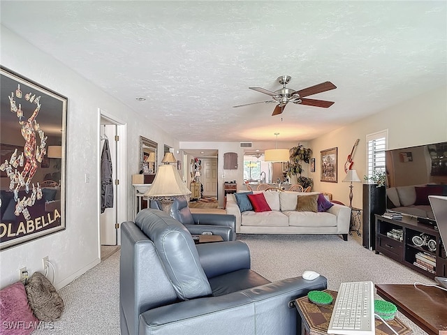 living room featuring a textured ceiling, light colored carpet, and ceiling fan