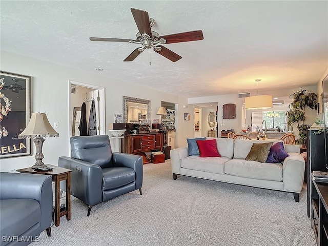 carpeted living room featuring a textured ceiling and ceiling fan