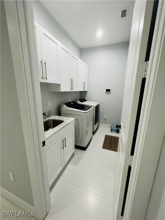 clothes washing area featuring light tile patterned floors, cabinets, sink, and separate washer and dryer