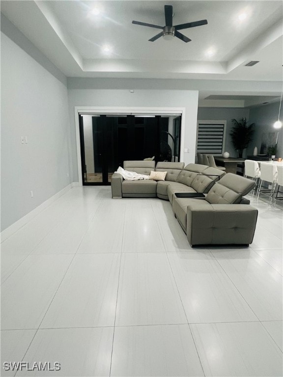 living room with tile patterned floors, a tray ceiling, and ceiling fan