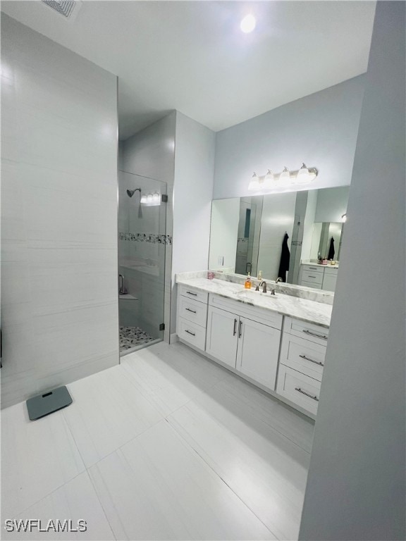 bathroom with vanity, tile patterned flooring, and tiled shower