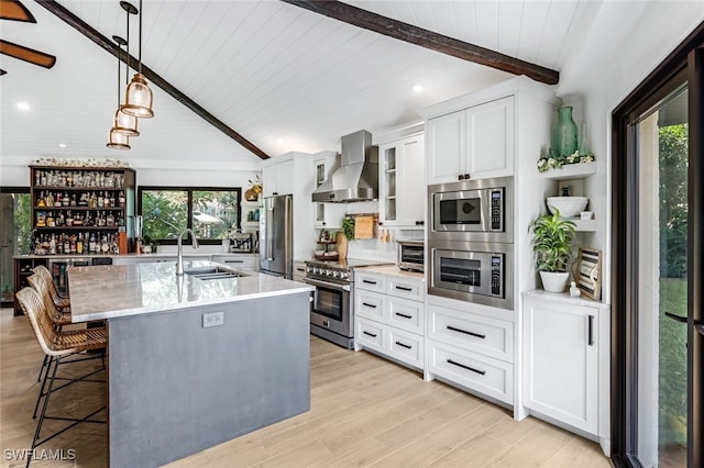 kitchen with appliances with stainless steel finishes, wall chimney exhaust hood, sink, a center island with sink, and plenty of natural light