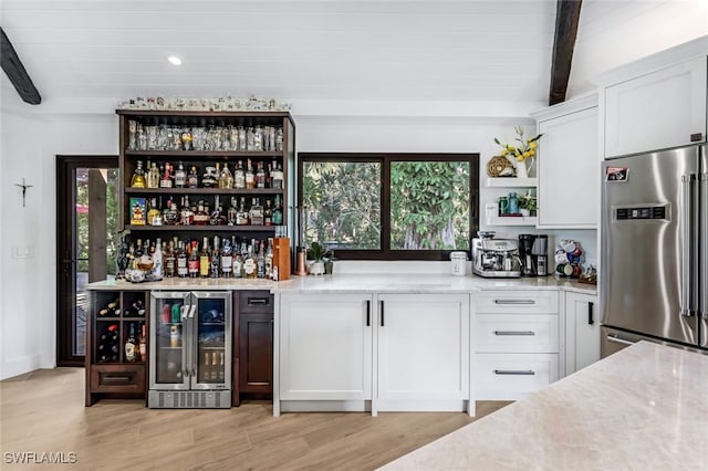 bar with white cabinets, high end fridge, beamed ceiling, and plenty of natural light