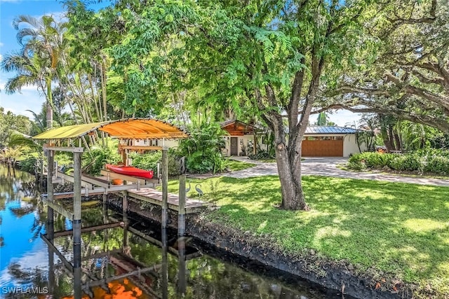 view of dock with a lawn and a water view