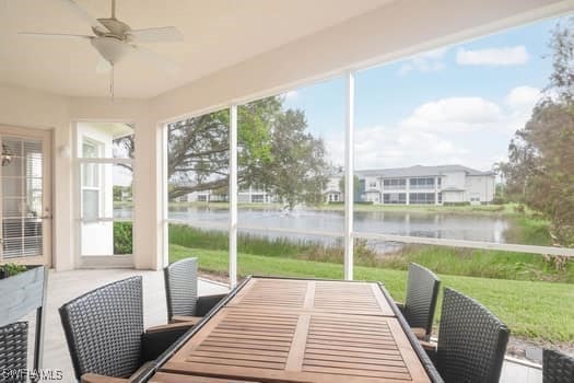 sunroom / solarium with ceiling fan and a water view