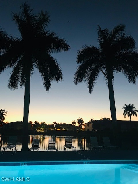 pool at dusk featuring a water view