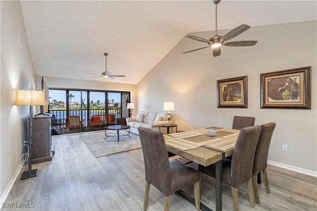 dining room featuring hardwood / wood-style flooring, high vaulted ceiling, and ceiling fan