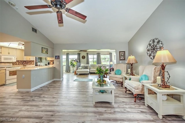 living area featuring high vaulted ceiling, visible vents, baseboards, a ceiling fan, and light wood-type flooring