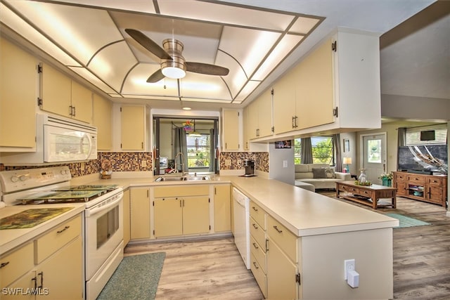 kitchen with a healthy amount of sunlight, sink, white appliances, and kitchen peninsula