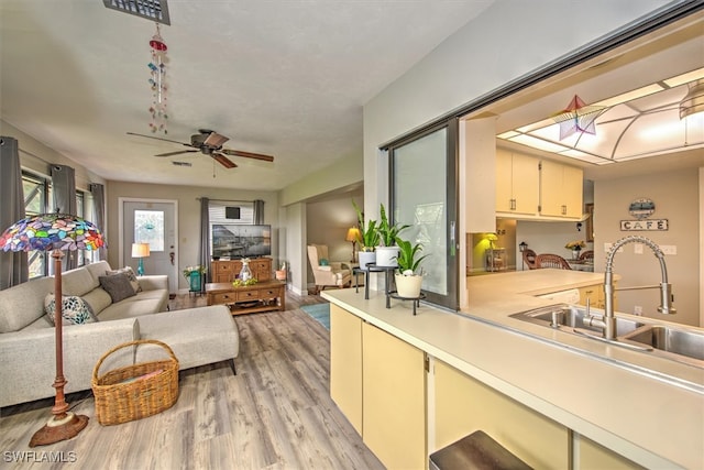 living room with ceiling fan, sink, and light wood-type flooring