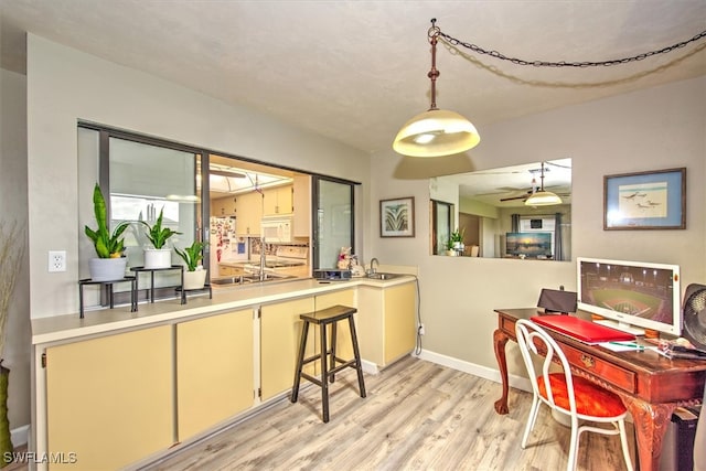 dining space featuring ceiling fan, sink, and light wood-type flooring