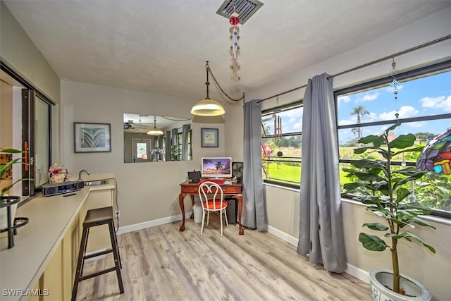 dining space with ceiling fan, sink, and light wood-type flooring