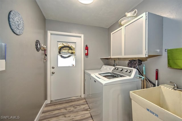 washroom with cabinets, independent washer and dryer, light hardwood / wood-style flooring, and sink