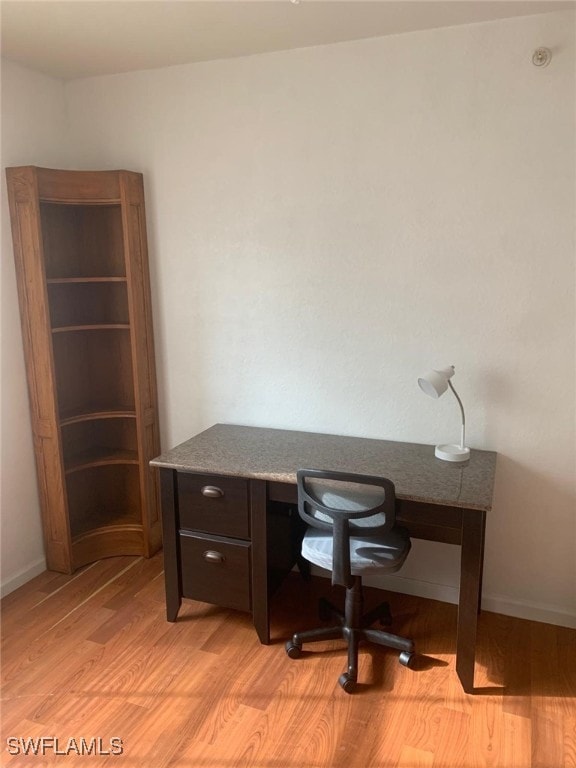 office with built in desk and light wood-type flooring