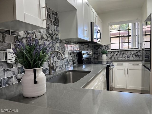 kitchen featuring tasteful backsplash, appliances with stainless steel finishes, sink, and white cabinets