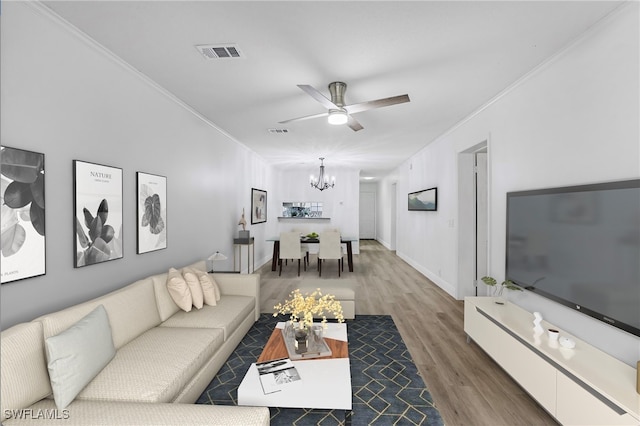 living room with hardwood / wood-style floors, ceiling fan with notable chandelier, and crown molding