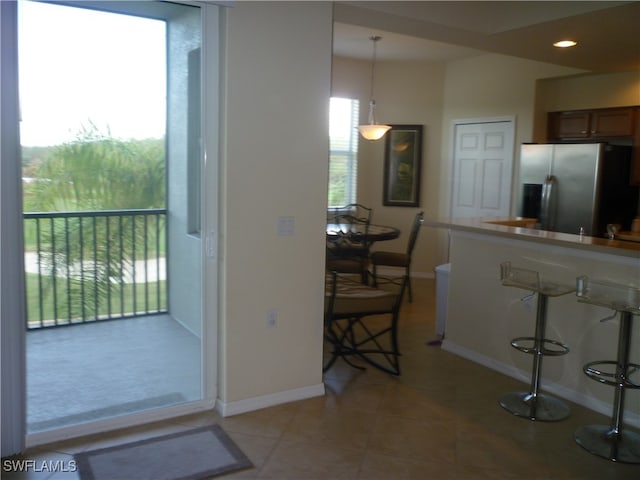 kitchen with light tile patterned flooring, stainless steel fridge, and decorative light fixtures