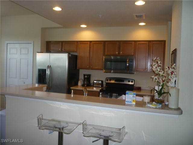 kitchen featuring kitchen peninsula, stainless steel appliances, and a kitchen bar