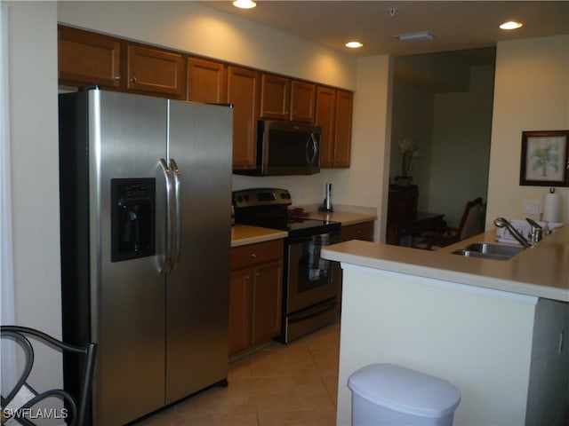 kitchen featuring sink, kitchen peninsula, stainless steel appliances, and light tile patterned floors