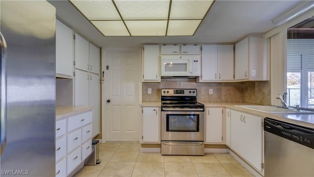 kitchen with white cabinets, light tile patterned floors, stainless steel appliances, and sink