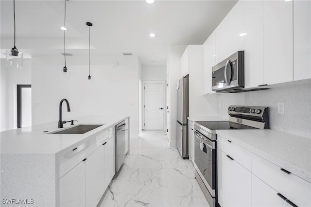 kitchen with a center island with sink, hanging light fixtures, appliances with stainless steel finishes, white cabinetry, and sink