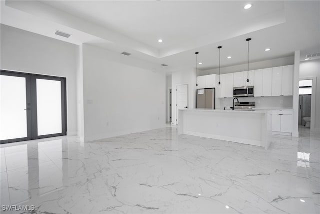 unfurnished living room with french doors and a tray ceiling