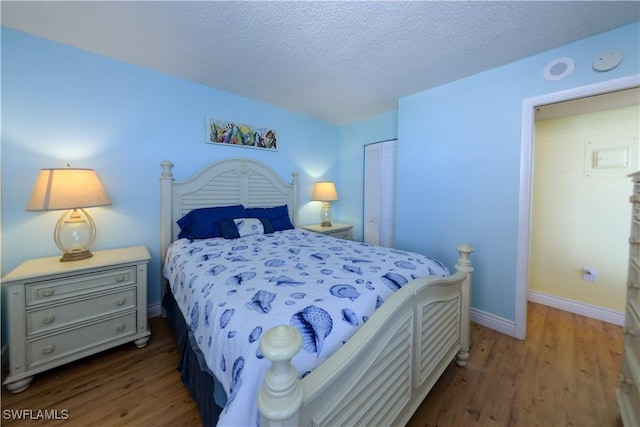 bedroom featuring a closet, wood-type flooring, and a textured ceiling