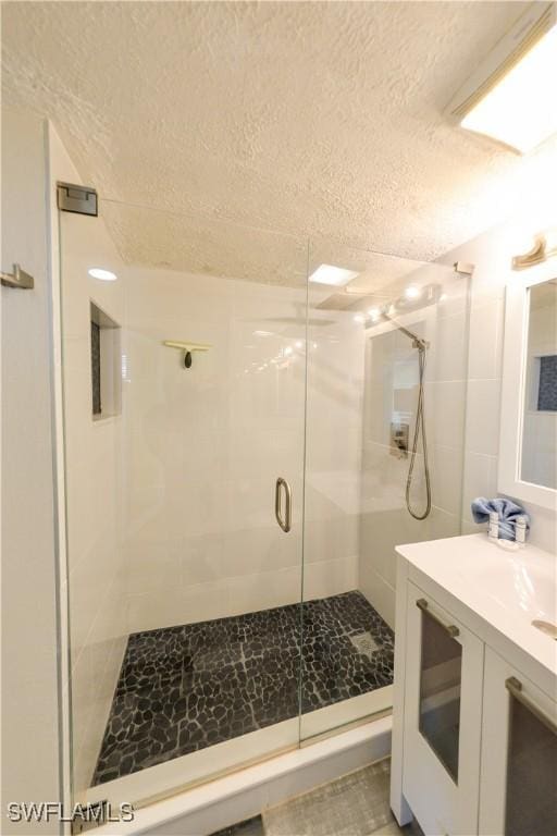 bathroom featuring a textured ceiling, vanity, and walk in shower