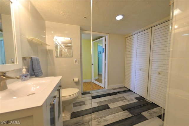 bathroom with a textured ceiling, vanity, and toilet