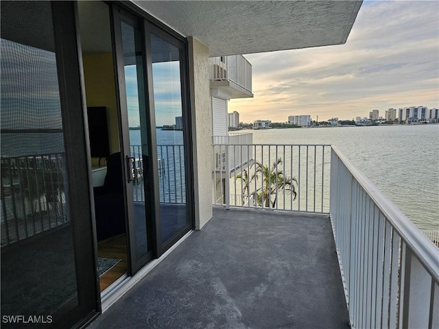 balcony at dusk featuring a water view