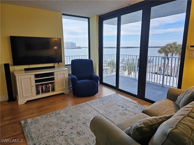 living room featuring hardwood / wood-style flooring, expansive windows, a water view, and a textured ceiling