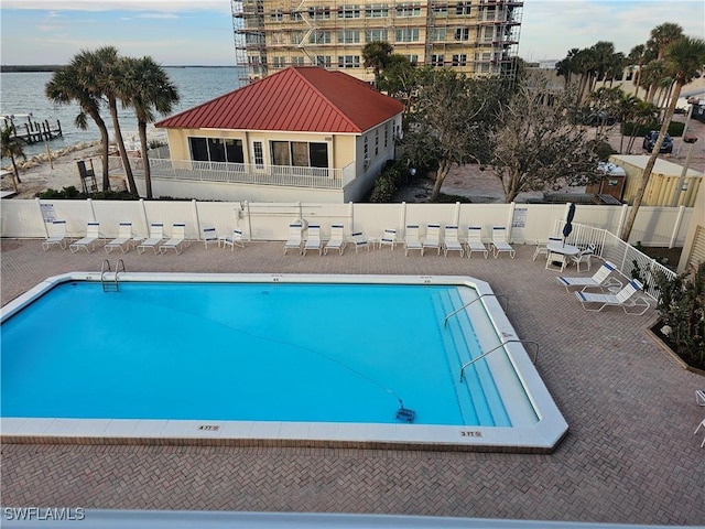 view of pool featuring a water view and a patio