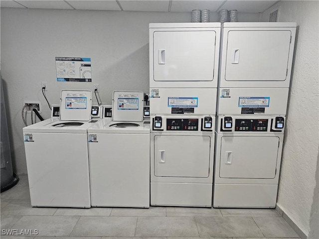 washroom with washing machine and dryer, stacked washing maching and dryer, and light tile patterned floors