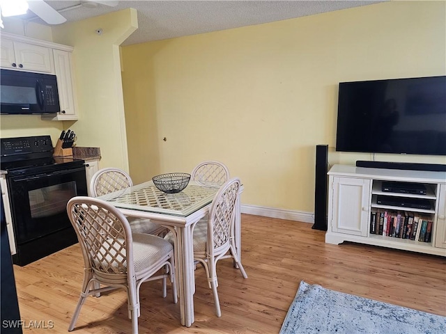 dining area with ceiling fan, light hardwood / wood-style flooring, and a textured ceiling