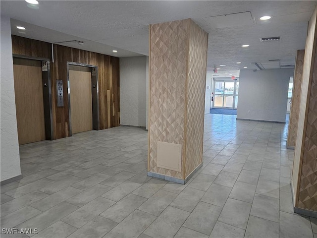 hallway featuring elevator and wooden walls